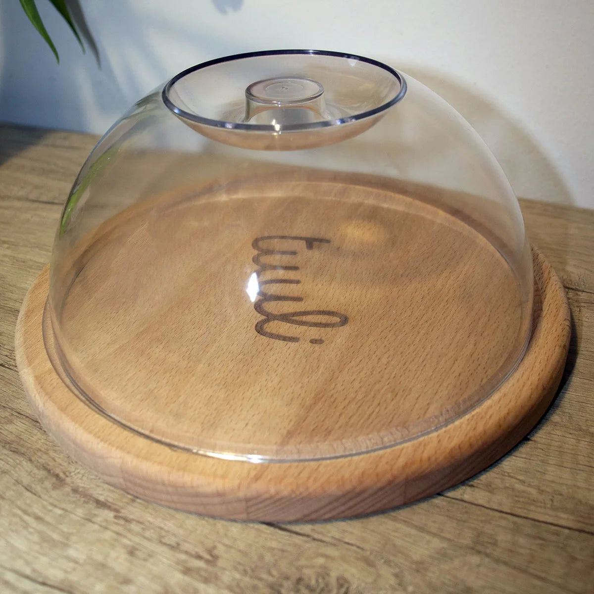 Wooden round cutting board with lid displaying artisanal cheeses and fruits