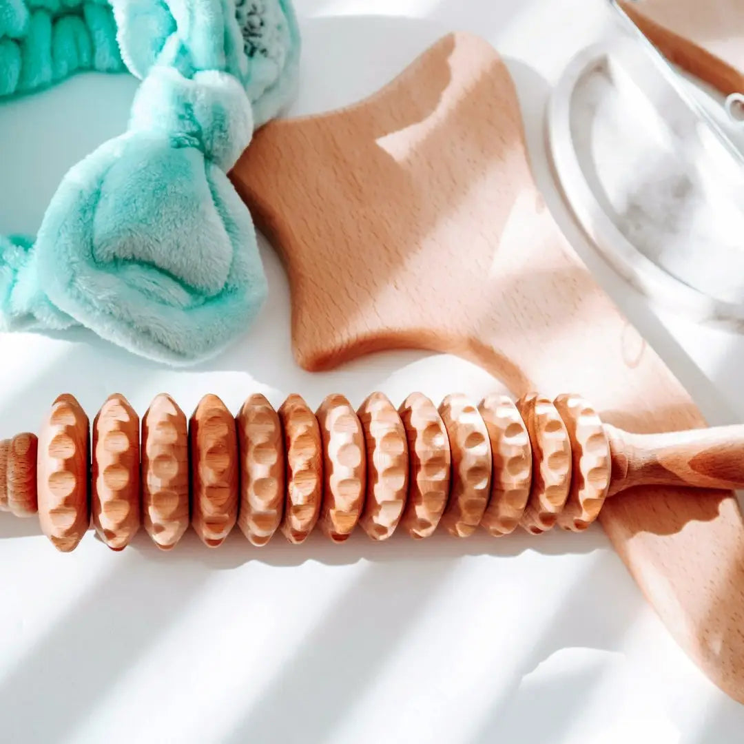 Assortment of wooden handheld massagers—foot roller, curved back roller, and body tools—natural beechwood on a neutral background, Tuuli collection